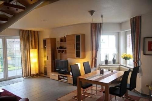 a living room with a table and a television at Ferienhaus Sandmann Greetsiel in Greetsiel