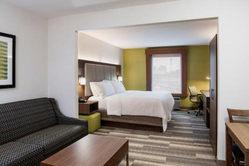 Holiday Inn Express Hotel & Suites Saskatoon, an IHG Hotel في ساسكاتون: غرفه فندقيه بسرير واريكه