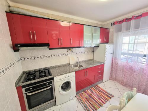 a kitchen with red cabinets and a washing machine at Apartamento Real Delux in Vila Real de Santo António