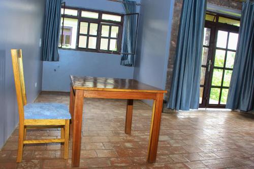 a wooden table and chair in a room with windows at Lake Chahafi Resort in Kisoro