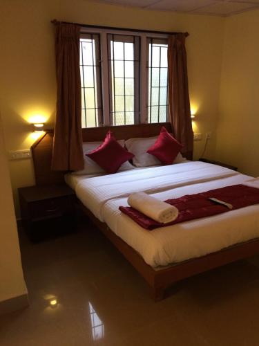 1 dormitorio con 1 cama grande con almohadas rojas en FLGHR Crescent Park, en Kodaikanal