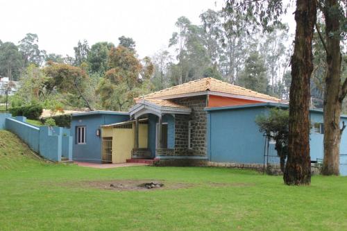 una casa azul en un patio con un árbol en FLGHR Crescent Park, en Kodaikanal