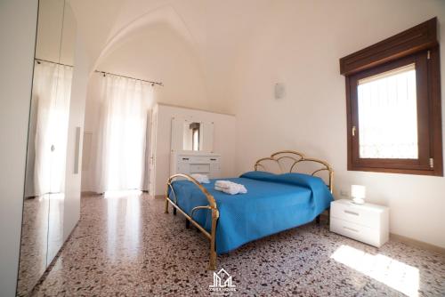 a bedroom with a blue bed and a window at Zaira House in Torre Suda