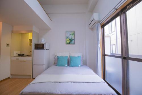 a bedroom with a bed with blue pillows and a window at 閑静な住宅街_暖かく居心地の良いデザイン EoW-7 in Tokyo