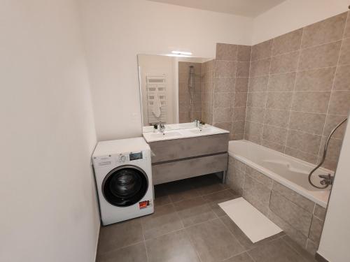 une salle de bain avec un lave-linge et une baignoire dans l'établissement Perle de Saint-Ouen - 6 à 8 personnes, à Saint-Ouen