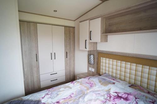 a bedroom with a bed and white cabinets at Stunning river view 2 bedroom caravan with decking in Hunstanton