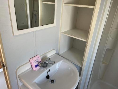 赫徹漢的住宿－Budget 3 Bedroom Caravan with Decking at Heacham，一间带水槽、镜子和书架的浴室