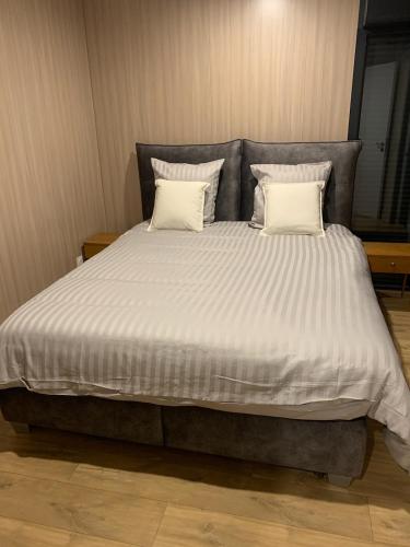 Elle comprend un grand lit avec des draps et des oreillers blancs. dans l'établissement Massassi Plaza, à Cornimont