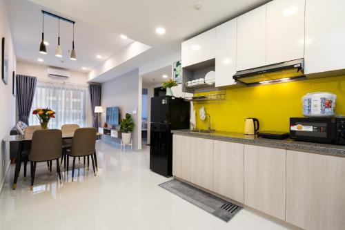 een keuken met een tafel en een gele muur bij Soho Apartment By Convinia in Ho Chi Minh-stad