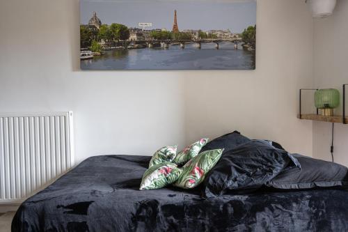 a bed with two pillows and a picture on the wall at Joli appartement dans Eco quartier résidentiel in Saint-Ouen