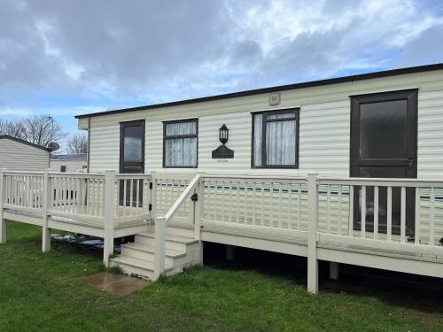 a white mobile home with a porch and a deck at 2 Bedroom caravan Hunstanton pets go free in Hunstanton