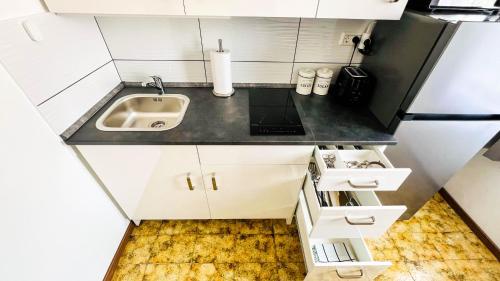 eine kleine Küche mit weißen Schränken und einem Waschbecken in der Unterkunft Rooms Koblar in Portorož