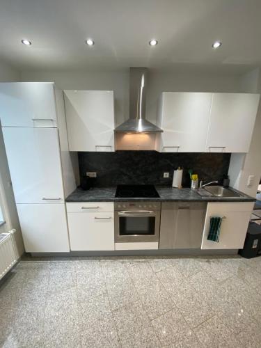 a kitchen with white cabinets and a stove top oven at Apartment Kompakt Gottschalk in Kassel