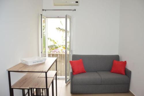 een bank met twee rode kussens naast een tafel bij Casa vacanze VIA ROMA 57 in Marsala