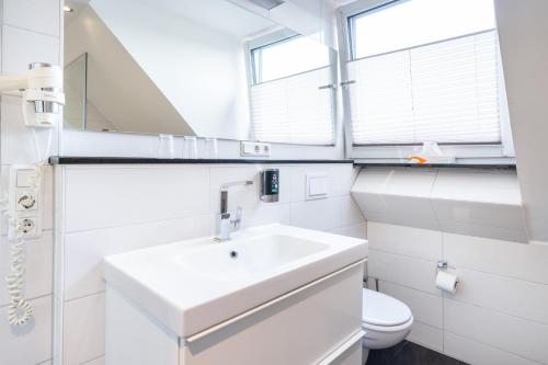 a white bathroom with a sink and a toilet at HOTEL Am Spichernplatz in Düsseldorf
