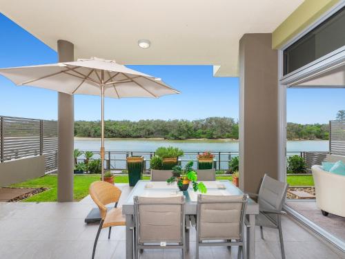 a patio with a table and chairs and an umbrella at Bare Feet Retreat in Kingscliff