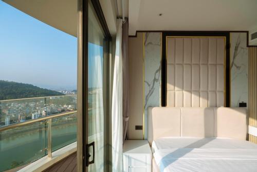 Khách sạn cao cấp citadines marina HẠ LONG في ها لونغ: غرفة نوم بسرير ونافذة كبيرة