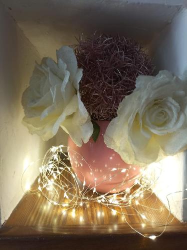 a vase with two flowers on a table with lights at CASA VACANZE - LA CASINA DI LALLA - Greccio in Greccio