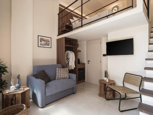 uma sala de estar com uma cadeira azul e uma televisão em Copal Experience The Port em Chania Town