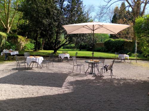 a table and chairs with an umbrella in a park at Hotel Casona El Arral in Liérganes