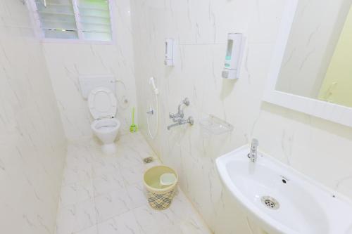a white bathroom with a toilet and a sink at Izi Transit Stay in Chennai