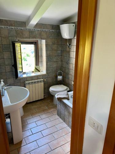 baño con lavabo y aseo y ventana en La Vista, en Otricoli