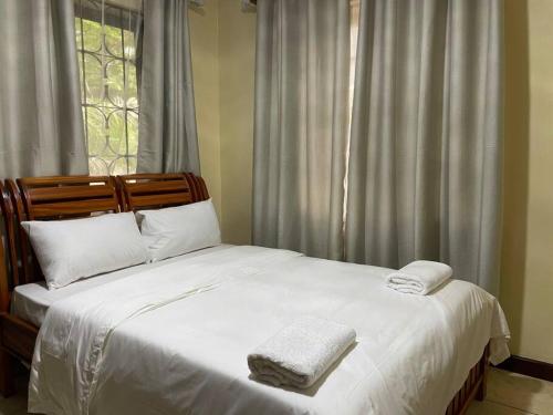 a bed with two towels on it in front of a window at Beautiful 4 bedroom house in Masaki with parking in Dar es Salaam