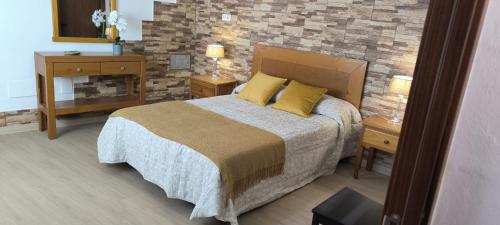 1 dormitorio con 1 cama con almohadas amarillas y pared de ladrillo en Casa Chemar, en La Orotava