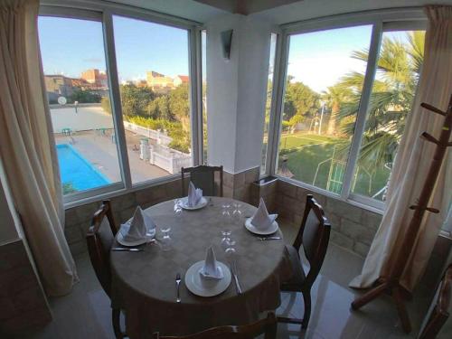 a dining room with a table with chairs and windows at Hotel Rais in El Marsa