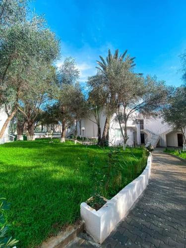 a park with green grass and trees and a sidewalk at Hotel Rais in El Marsa