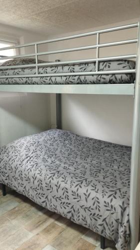 deux lits superposés avec des draps noirs et blancs dessus dans l'établissement studio 1 étoile paisible,4 couchages,jardin privé, à Les Adrets-de-l'Estérel