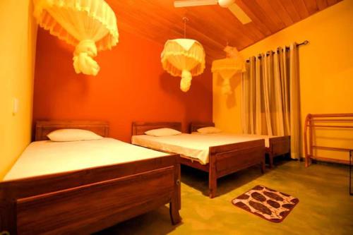 twee bedden in een kamer met oranje muren bij Sakura Holiday Home in Anuradhapura