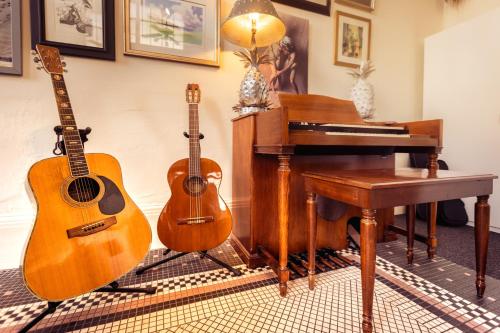 two acoustic guitars sitting next to a piano and a guitar at Luxury Living in Historic Bank Haven of Art&Music in Tomales