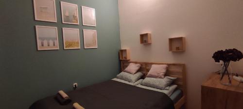 sypialnia z łóżkiem z poduszkami i obrazami na ścianie w obiekcie BudaWestHouse w mieście Budakeszi