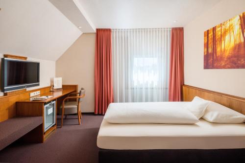 a hotel room with a bed and a desk and a television at Hotel Straubs Schöne Aussicht in Klingenberg am Main