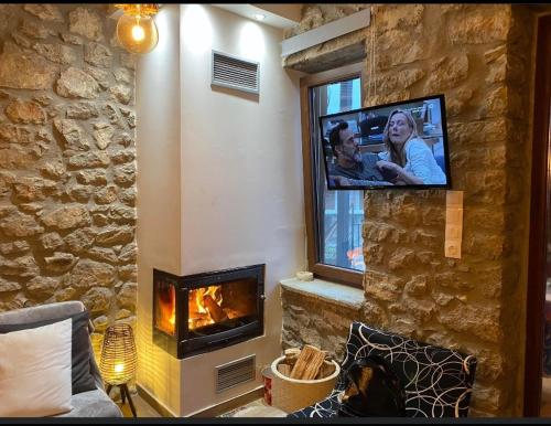 a living room with a fireplace and a tv on a wall at ΧΑΡΟΥΛΑ ΣΤΟΥΝΤΙΟ 2 in Pávliani