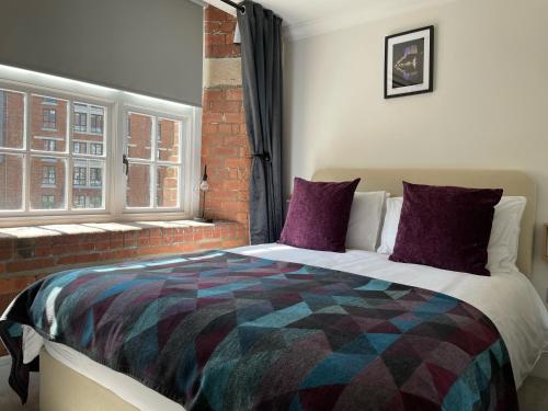a bedroom with a bed with purple pillows and a window at Staycation York at Cocoa Suites in York