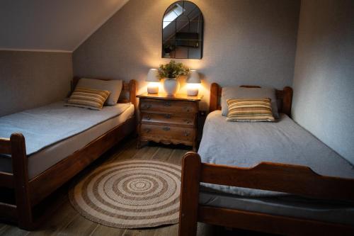 a bedroom with two beds and a dresser with a mirror at Pensjonat Zakątek in Lidzbark