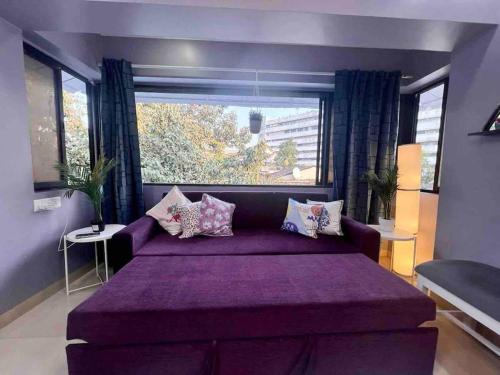 a purple bed in a room with a large window at Newton Villa, A Hidden Gem with a Pvt Terrace in the Heart of Bandra by Connekt Homes in Mumbai