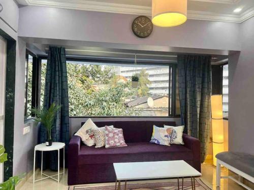 uma sala de estar com um sofá roxo e uma janela em Newton Villa, A Hidden Gem with a Pvt Terrace in the Heart of Bandra by Connekt Homes em Mumbai