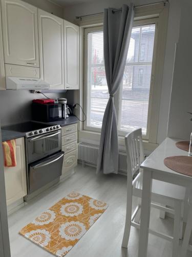 a kitchen with white cabinets and a table and a window at Yksiö+autopaikka/Small apt.+free parking in Hyvinkää
