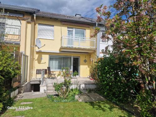 a yellow house with a balcony and a yard at Sarahs Ferienhaus in Raunheim