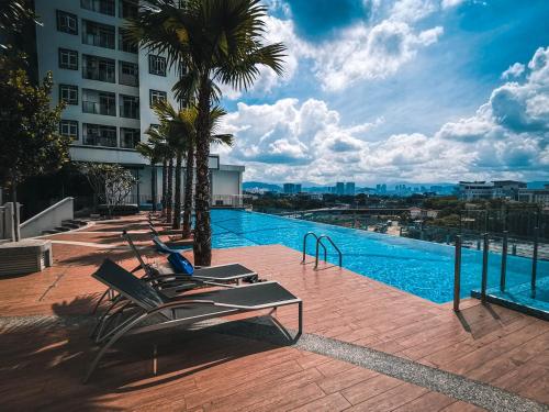 a swimming pool with chairs and palm trees on a building at TR Residence WTC Titiwangsa Monorail MRT Station KLCC HKL IJM Bukit Bintang in Kuala Lumpur