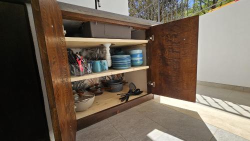 Habitación con armario de madera con platos y tazones. en Piuma Mobilehome, en Cardedu