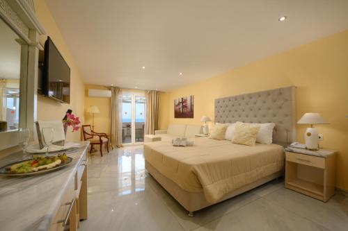 a bedroom with a large bed and a kitchen at Cavomarina Beach- Adults Only in Kavos