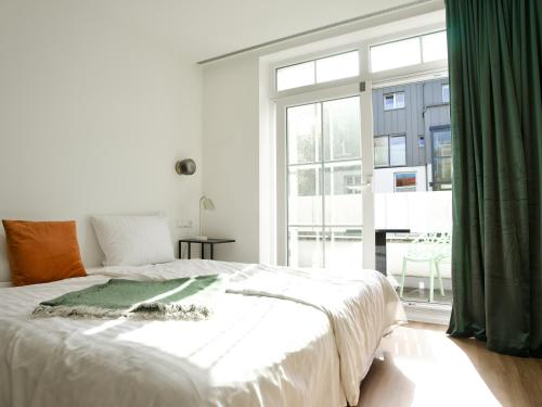a bedroom with a large bed and a large window at Apartmenthaus Hamburg Les Jardins in Hamburg
