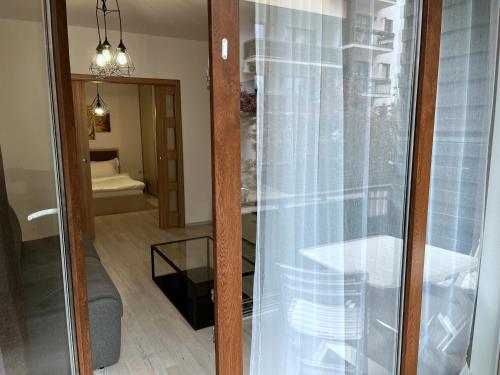 a room with a glass door with a table and a mirror at RBC Apartments with garden view in Cluj-Napoca