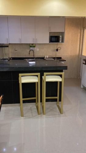 a kitchen with a sink and two stools at JUCENTE_ALOJAMENTO_LOCAL in Quifica