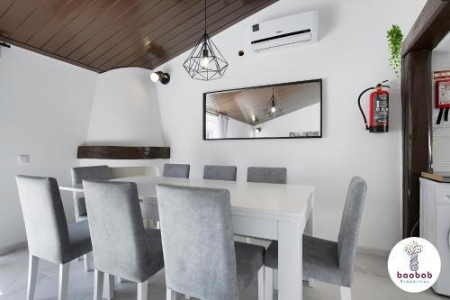 een eetkamer met een witte tafel en stoelen bij Charming Villa Sam in Albufeira