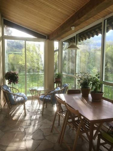 une véranda avec des tables, des chaises et des fenêtres. dans l'établissement Belle maison de campagne familiale - 8 personnes, à Lachau